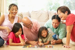A family smile while playing a board game with one another. This could represent the bonds cultivated by working with a parenting counselor in Arcadia, AZ. Learn more about internal family systems therapy in Arcadia, AZ and other services by searching for family Christian counseling center of Phoenix today. 