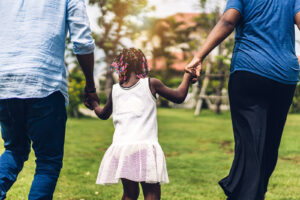 Two parents hold the hands of their child walking in between them. Learn how family counseling Phoenix can offer support by contacting a parenting counselor in Arcadia, AZ. The family christian counseling center of phoenix can offer support today.