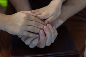 A close up of hands joining together hover a book. Christian marriage counseling AZ can offer support by contacting a therapist in Arcadia, AZ. Search for Christian marriage counseling Phoenix to learn more.