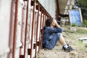 A child sits alone against a wall while covering their face. This could represent past trauma that a child therapist in Phoenix, AZ can address. Learn more about trauma therapy in Arcadia, AZ by searching for trauma therapy Phoenix or contacting an EMDR therapist in Phoenix, AZ today.