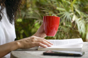 A person sits outside with a book and coffee mug. Grieving counseling in Phoenix, AZ can offer healing support. Search "trauma therapy phoenix" to learn more about counseling in Scottsdale AZ. 