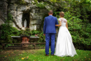 A couple in wedding attire stands before a stone shrine. Learn how a premarital counselor in Phoenix, AZ can help your marriage thrive. Contact a therapist in Arcadia, AZ to learn more. 