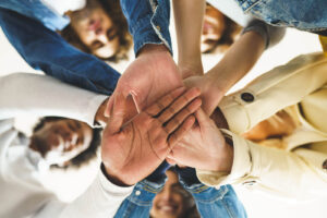A group of people put their hands in a group as they smile at the camera. This represents the support a therapist in Arcadia, AZ can provide with trauma therapy in Arcadia, AZ. Learn more about therapy in Arcadia, AZ and how trauma counseling in Phoenix, AZ can help.