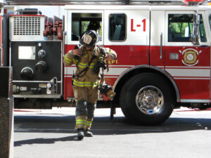 A firefighter takes off their equipment while walking away from a truck. Learn how a grief counselor in Phoenix, AZ can offer support for first responders by searching for grief counseling in Phoenix, AZ, and therapist in Phoenix, AZ. 